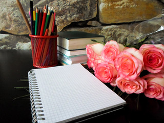 September 1 concept. Books, flowers, pencils on a black table. and white notebook. Back to school