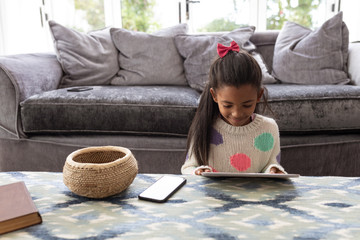 Girl using digital tablet on a table in living room