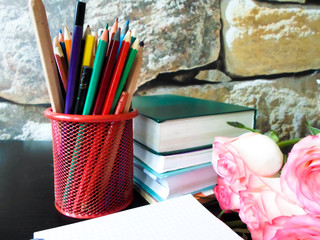 September 1 concept. Books, flowers, pencils on a black table. and white notebook. Back to school