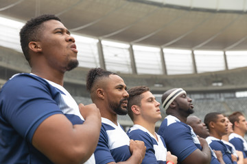 Group of diverse male rugby players taking pledge together in stadium