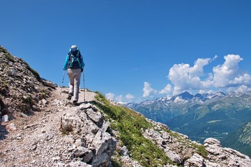 Naklejka na ściany i meble Low angle view of mature woman hiking in Brenta Dolomites in Italy