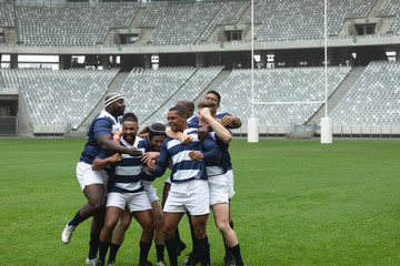 Group of diverse male rugby players celebrating goal in stadium