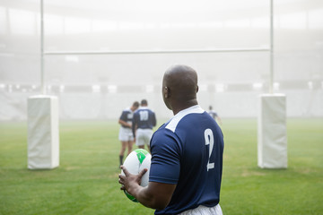 African american male rugby player holding a rugby ball in stadium