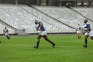 Group of diverse male rugby players playing rugby in stadium