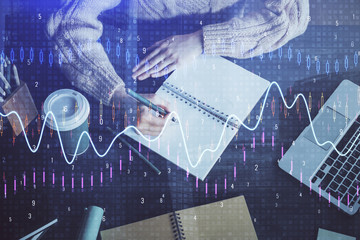 Forex graph on hand taking notes background. Concept of research. Double exposure