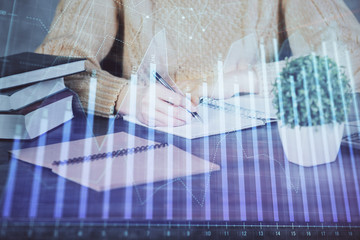 Forex graph on hand taking notes background. Concept of research. Double exposure