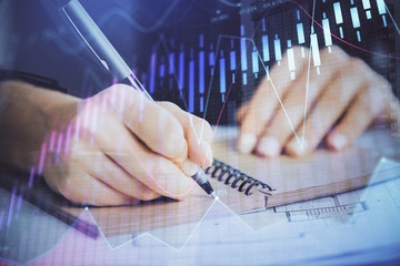 Forex graph on hand taking notes background. Concept of research. Double exposure