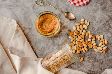 Creamy and smooth peanut butter in jar on gray table. Natural nutrition and organic food. Top view.Kinfolk and comfort food atmosphere concept.