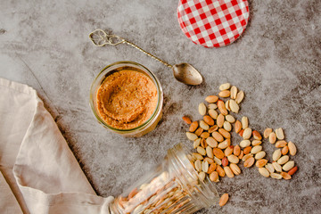 Creamy and smooth peanut butter in jar on gray table. Natural nutrition and organic food. Top...