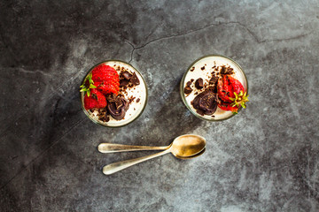 Italian dessert panna cotta decorated with fresh strawberry on a stone or slate background. Top...