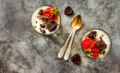 Italian vegan dessert panna cotta decorated with fresh strawberry and chocolate on a stone or slate background. Top view.Copy space