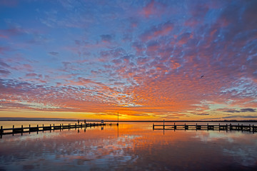 Red, orange and yellow sunset over jetty and river