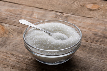 Fototapeta na wymiar Bowl of sugar with spoon on wooden table
