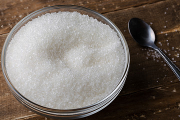 Bowl of sugar with spoon on wooden table