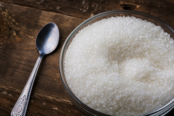 Bowl of sugar with spoon on wooden table