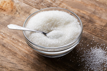 Bowl of sugar with spoon on wooden table