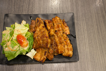 belly grilled pork japanese style called Hokkaido Buta with vegetables on black tray and wood table