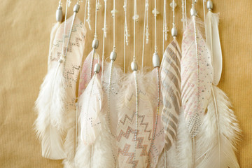 Closeup details dreamcatcher with painted silver light pink feathers on craft paper background