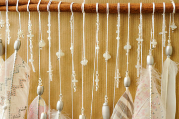 Closeup details dreamcatcher with painted silver light pink feathers on craft paper background