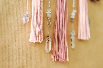 Closeup modern mandala with quartz crystals, amethyst, moonstone, tassels and chain on craft paper background