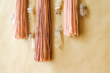 Closeup modern mandala with quartz crystals, amethyst, moonstone, tassels and chain on craft paper background