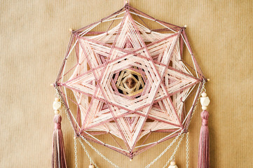 Closeup modern mandala with quartz crystals, amethyst, moonstone, tassels and chain on craft paper...