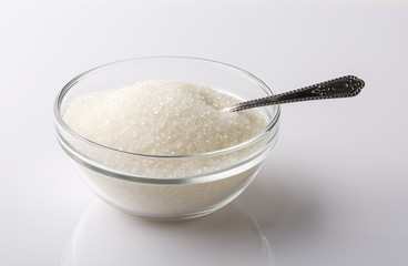 A glass bowl of sugar with spoon