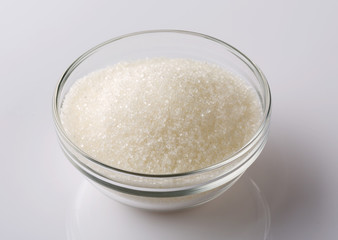 Glass bowl of sugar on white background