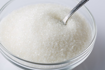 A glass bowl of sugar with spoon