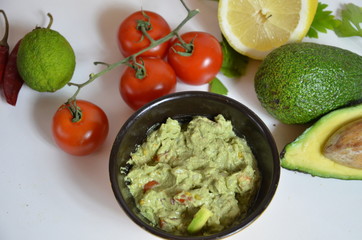 A delicious Bowl of Guacamole next to fresh ingredients on a table with tortilla chips and salsa. sandwich with guacamole, red hot pepper, lime, lemon, avocado