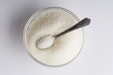 Fototapeta na wymiar Top view of sugar with spoon in a glass bowl