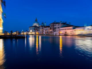 Fototapeta na wymiar View of Grand Canal and Basilica della Salute at night with boat night trails with radial blur