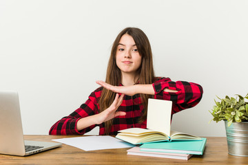 Young teenager going back to her routine doing homeworks showing a timeout gesture.