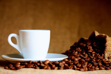 White cup and coffee beans on a blurred background.