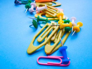Multicolored latch clips scattered across a turquoise background. View from above. The concept is time to school.