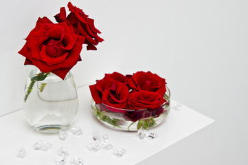 Red roses buds flowers on glass vases on white shelf