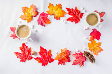Autumn composition concept background. Cappuccino coffee or hot chocolate cup, with autumn bright leaves, pine cones, marshmallows. Flatlay on white background, simple top view pattern
