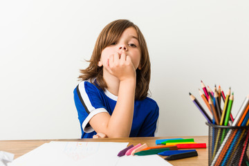 Little boy painting and doing homeworks on his desk relaxed thinking about something looking at a copy space.