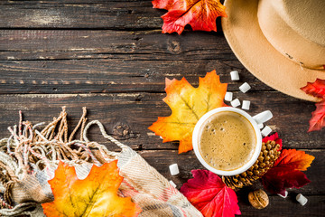 Naklejka na ściany i meble Autumn composition concept background. Cappuccino coffee or hot chocolate cup, with autumn bright leaves, pine cones, marshmallows. Flatlay on wooden rustic background, simple top view pattern