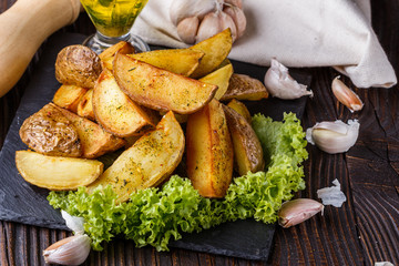 Potato wedges baked in their skins with lettuce on wooden background.
