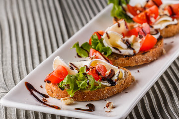 Bruschetta with tomatoes, lettuce, camambert, balsamic vinegar