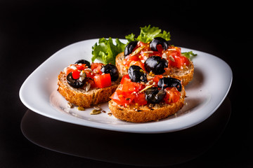 Italian bruschetta with tomato, black olives, lettuce and mustard