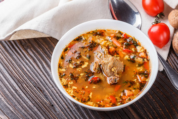 Georgian soup. Kharcho with rice, tomato, beef, garlic and herbs in bowl on wooden table