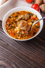Georgian soup. Kharcho with rice, tomato, beef, garlic and herbs in bowl on wooden table