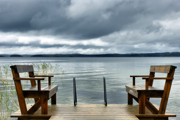Landscape in blue. Two wooden benches by the lake. Silence, calm, peace. Scandinavian lifestyle.