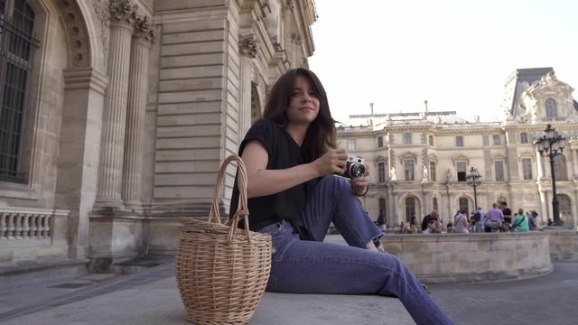 Beautiful young woman with dark hair, wearing jeans and black t-shirt is taking pictures of the city. Left to right pan real time portrait shot