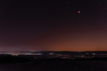 Fototapeta premium Sonnenuntergang in der Berglandschaft mit Mondfinsternis