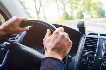 The driver's hands on the steering wheel of the car