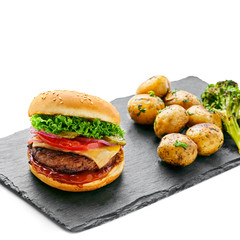                    Cheeseburger made of meat burger, cheese, tomato, lettuce, onion and pickled cucumber with baked potato and broccoli isolated on white background.