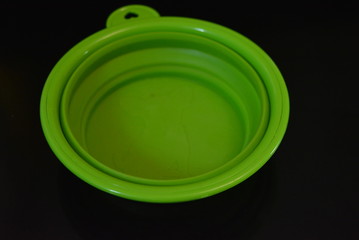 Green folding and multifunctional rubber plate, a bowl with a plastic edging on a black glossy surface.